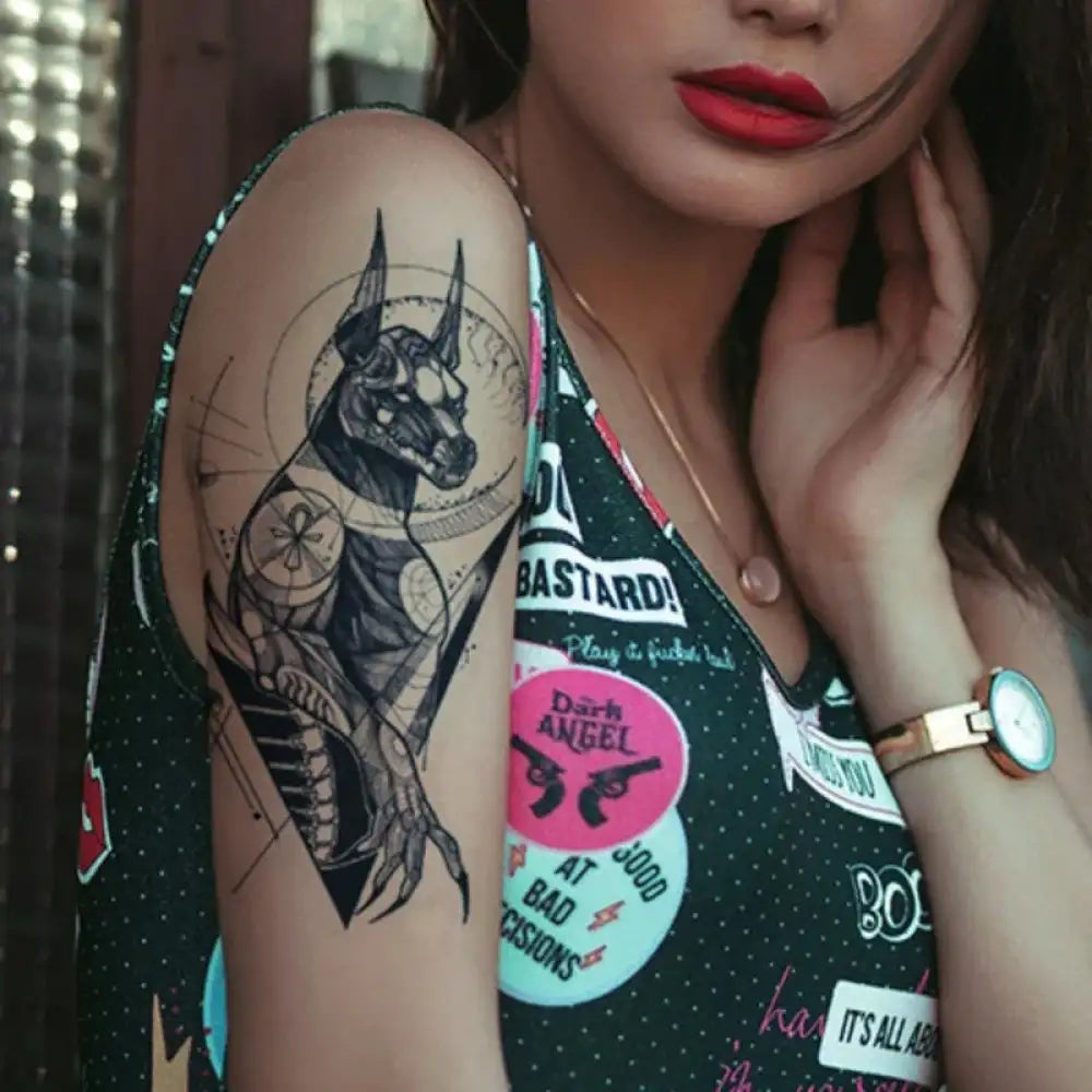 Woman’s arm featuring a stylized black Ancient Egyptian Anubis tattoo sticker with colorful patches