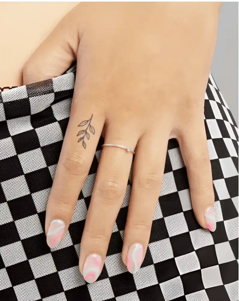 Tattoo sticker featuring a delicate leaf design on pinky with branches light moon theme