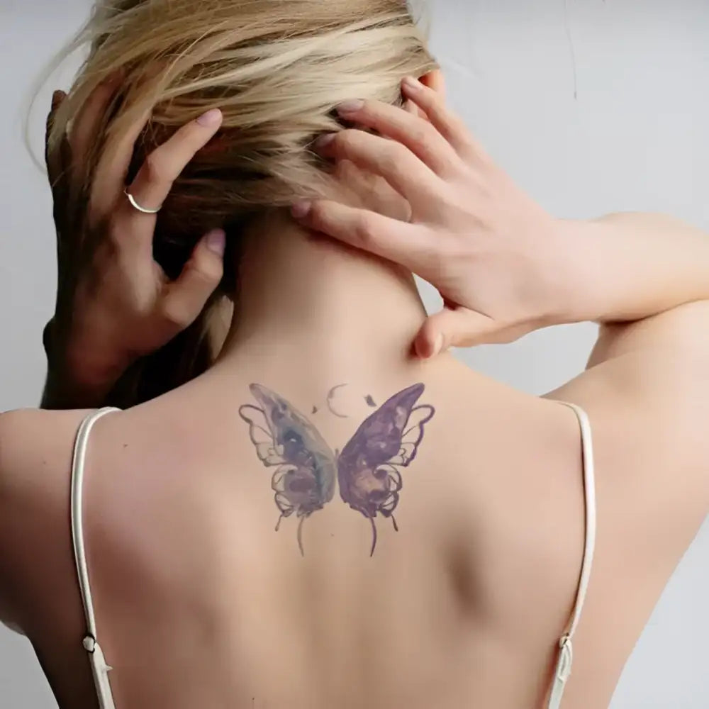 Blonde woman’s back with butterfly tattoo sticker from Iridescent Chrysalis featuring advanced hand-drawn design