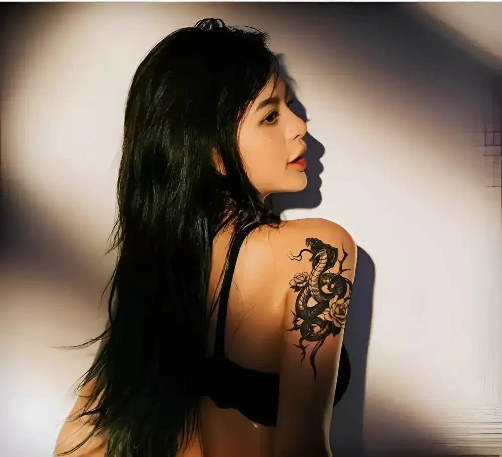 Woman with long black hair showcasing a snake and rose temporary tattoo sticker on her shoulder