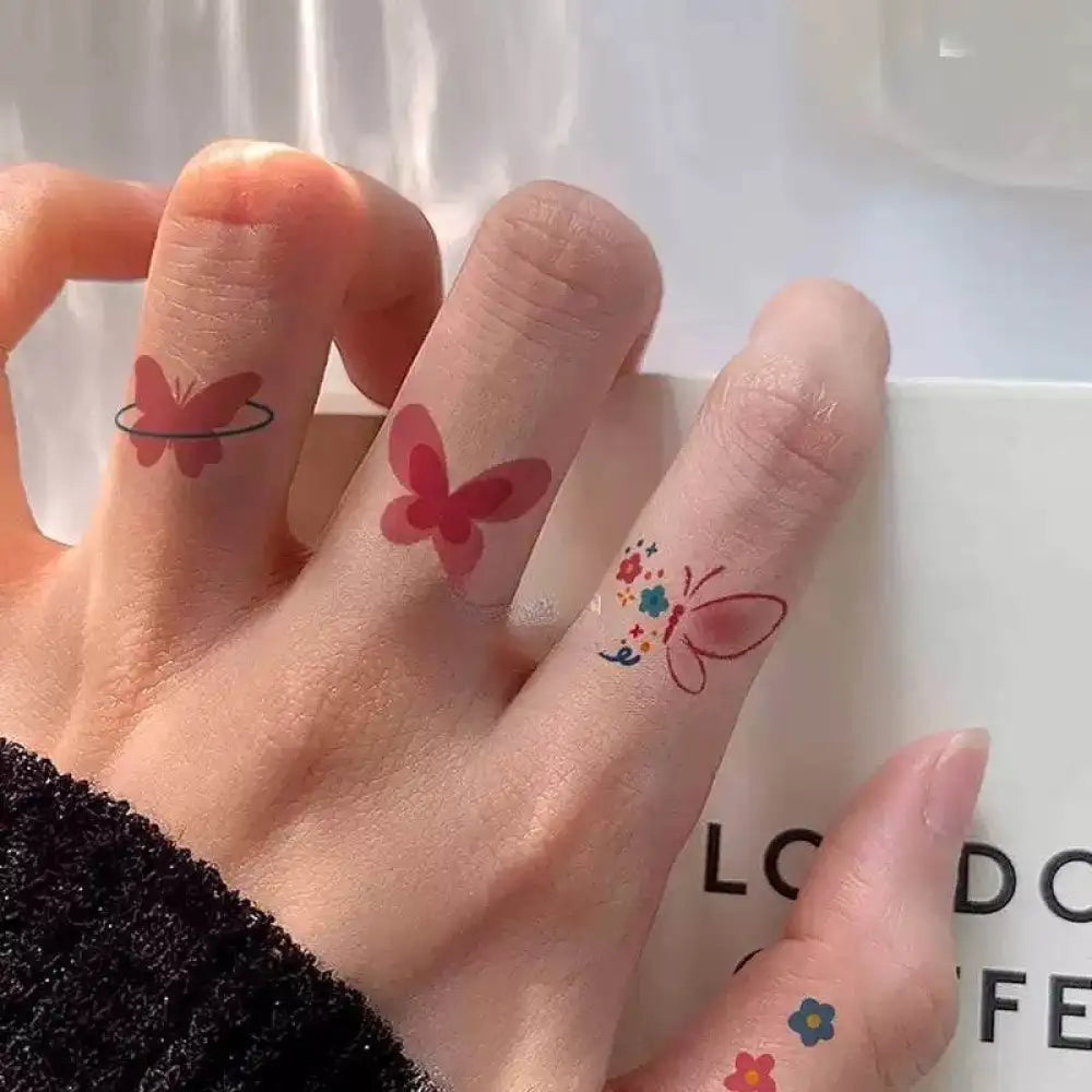 Small red butterfly tattoo sticker designs with floral accents on fingertips