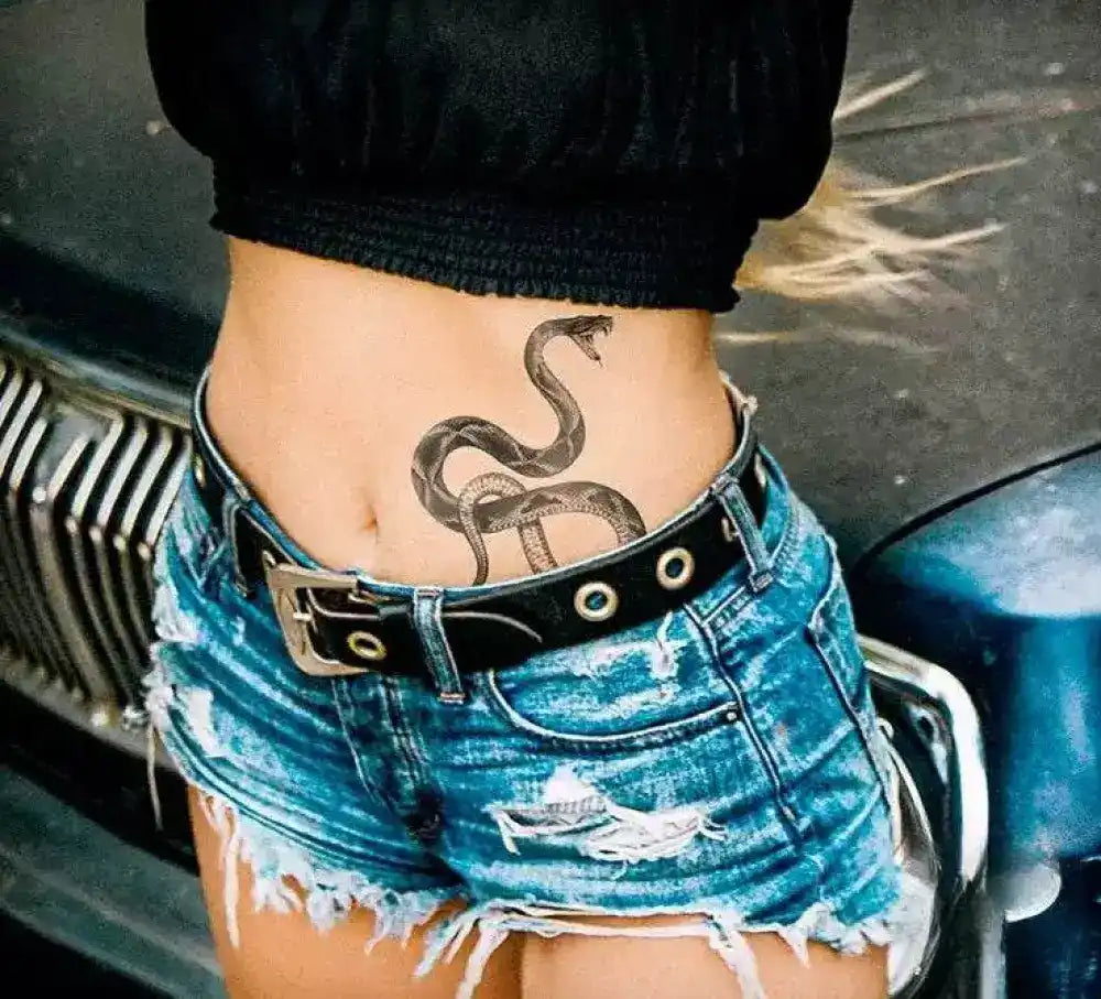 Woman’s midriff with snake temporary tattoo, ripped denim shorts, black belt