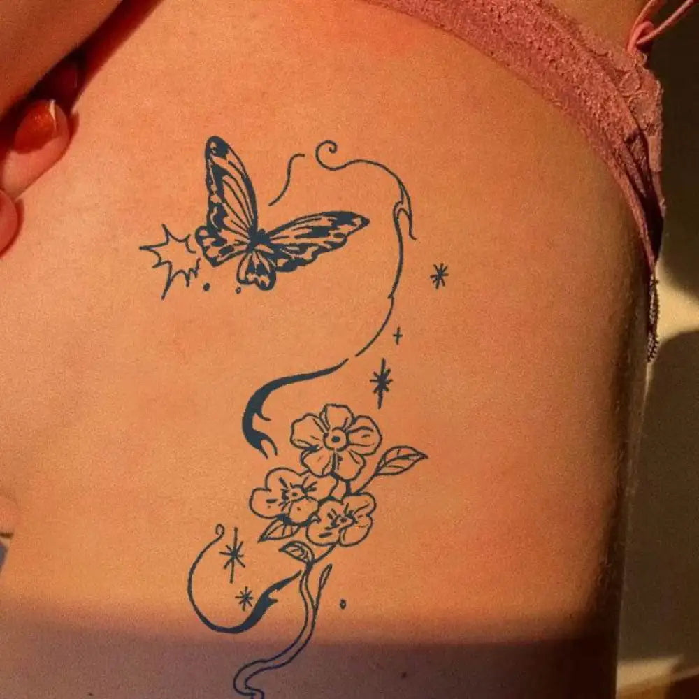 Ephemeral Bloom tattoo sticker featuring black outline butterfly, vines, flowers, stars on thigh