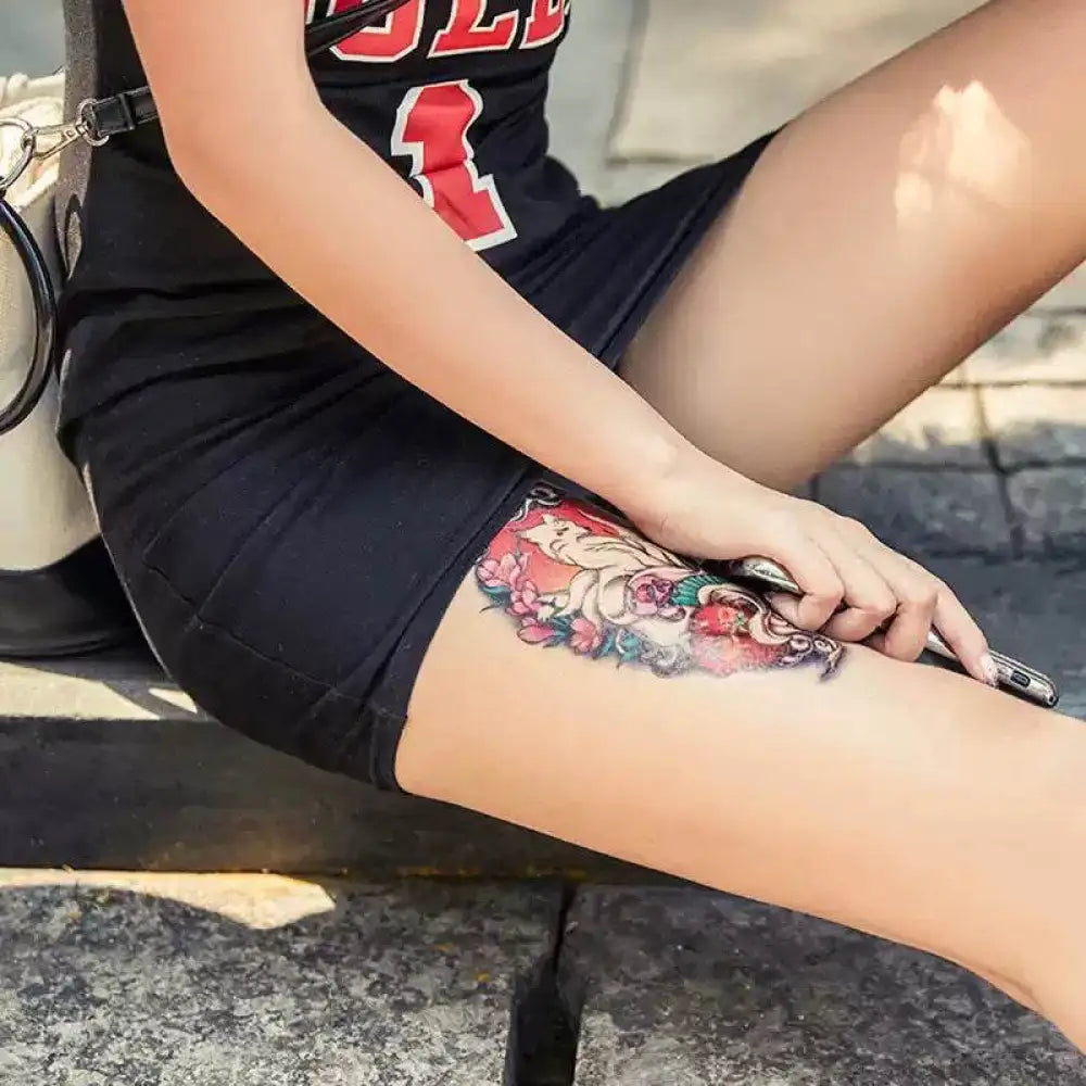 Woman’s thigh with colorful Mystical Fox temporary tattoo sticker featuring florals, real reviews
