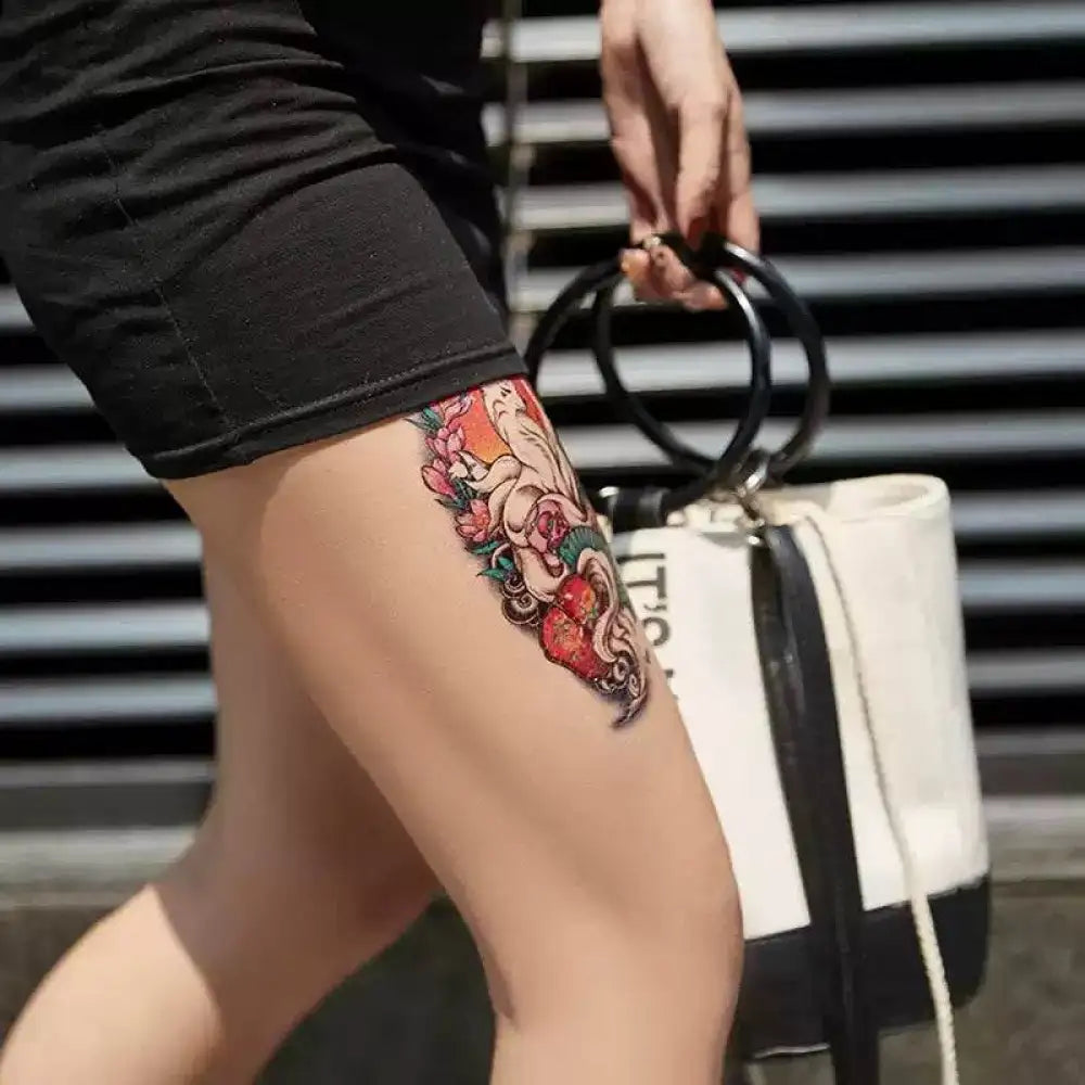 Colorful temporary tattoo sticker of octopus and flowers on woman’s thigh from Mystical Fox collection