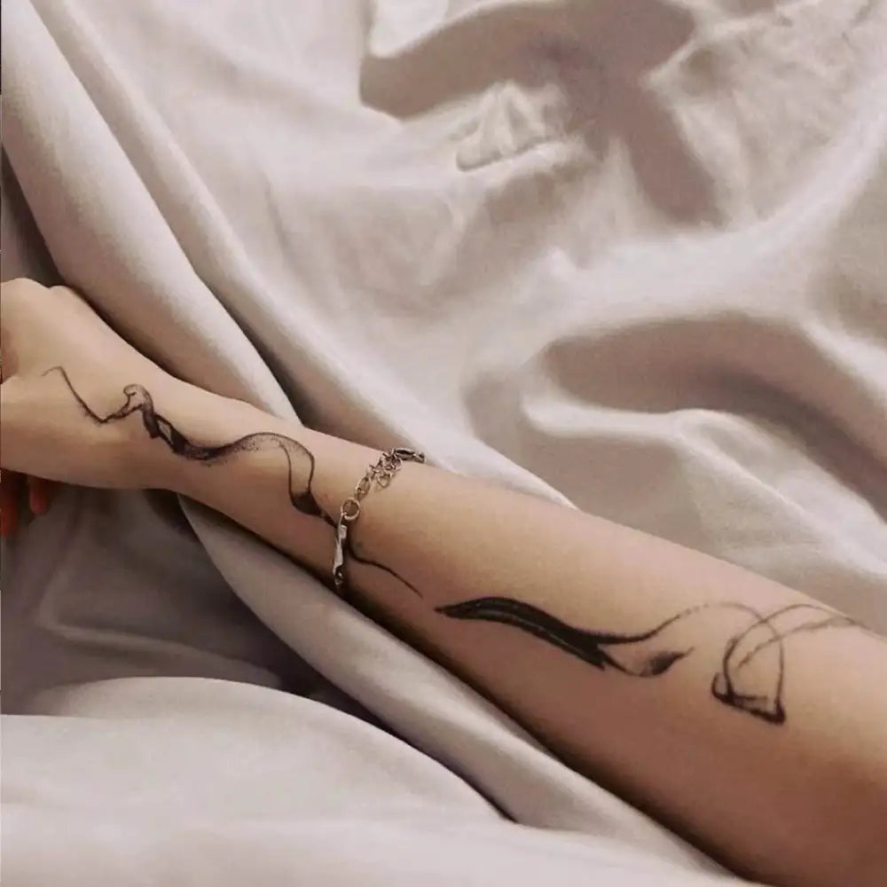 Rose line tattoo sticker on arm with black flowing line design and gold bracelet